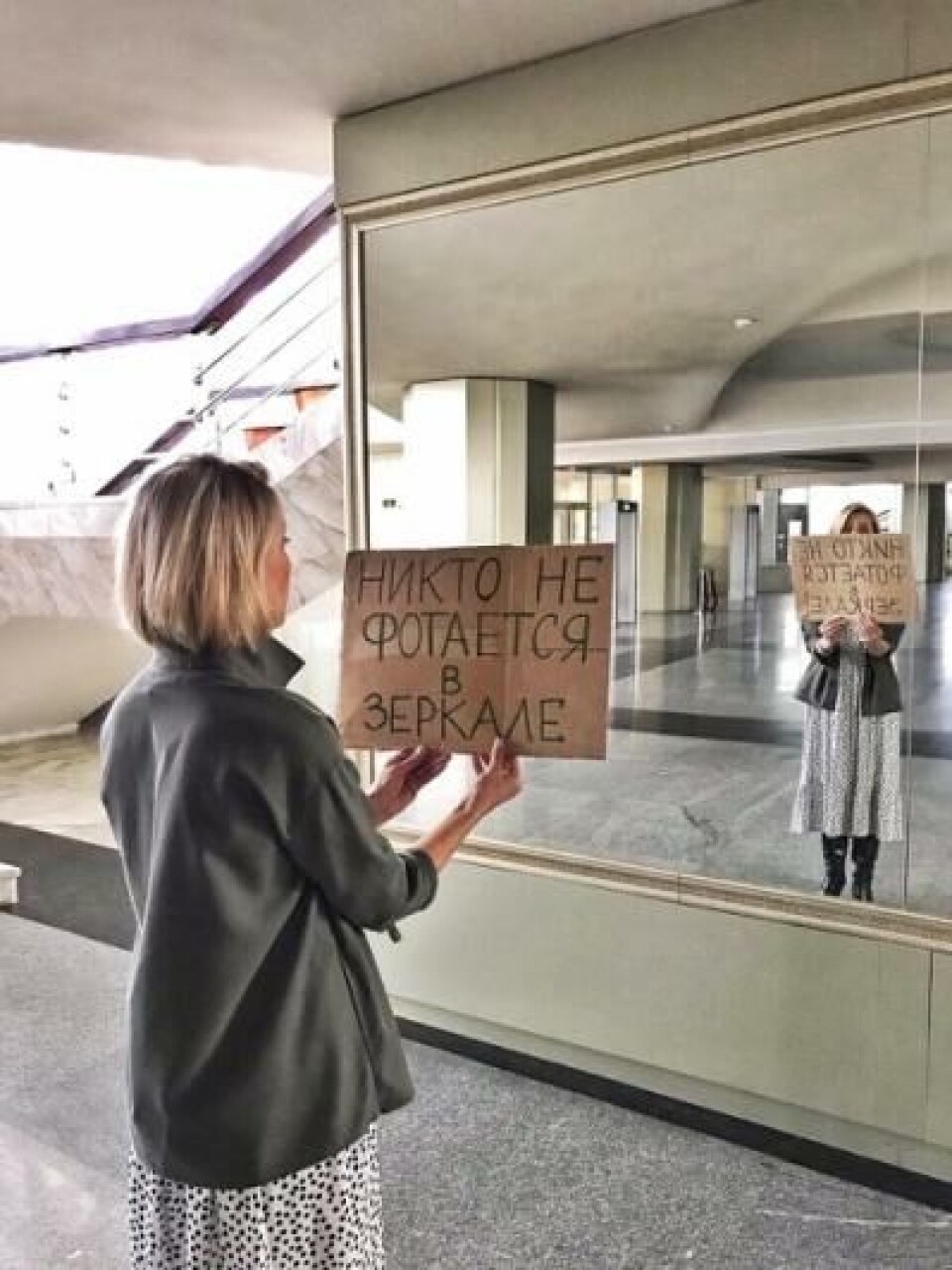 Kvinne med plakat der det står «Ingen som tar bilde i speilet»